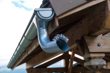 Metal drain pipe in the wing of a mountain cabin roof.