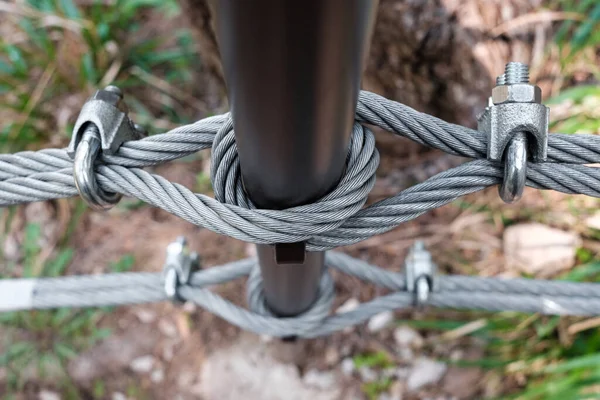 Interlocking steel cable secures a barrier on a mountain path.