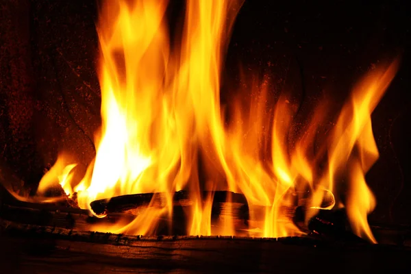 Fuego en una chimenea, llamas de fuego sobre un fondo negro —  Fotos de Stock