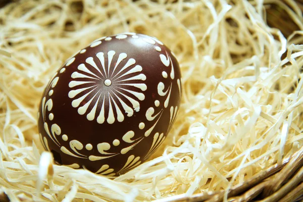 Закрашенное пасхальное яйцо в корзину с соломой, пасхальный фон — стоковое фото