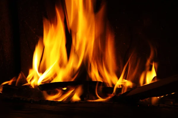 Fuego en una chimenea, llamas de fuego sobre un fondo negro — Foto de Stock