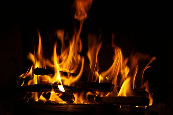 Fogo em uma lareira, chamas de fogo em um fundo preto — Fotografia de Stock