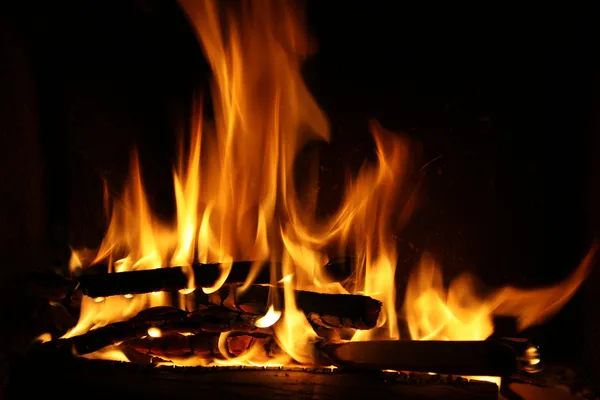 Fuego en una chimenea, llamas de fuego sobre un fondo negro — Foto de Stock