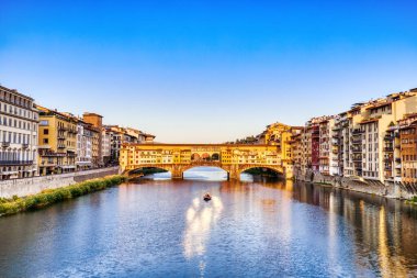Golden Sunset over Ponte Vecchio Bridge with Traditional Boat on the Arno River, Florence, Italy