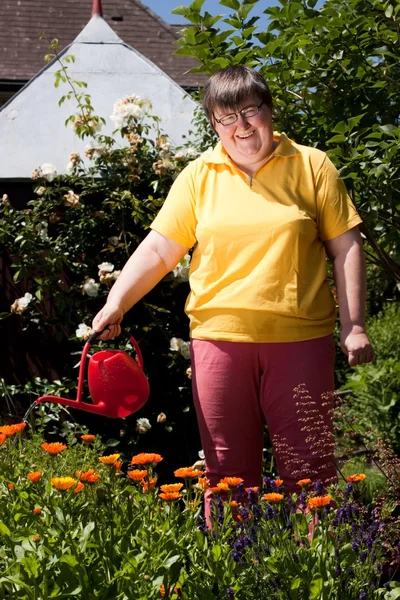 Disabled woman with a pot pours flowers — Stock Photo, Image