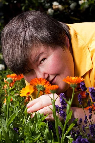 Disabled woman lying on grass and smell of flowers — Stockfoto