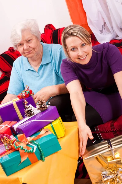 Female senior and pretty daughter become a lot of gifts — Stock Photo, Image