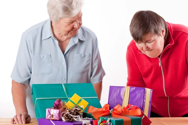 Senior with mentally handicapped woman consider gifts — Stock Photo, Image