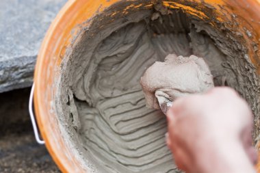 Man laying on cement mixed in a bucket