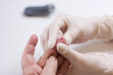 Geriatric nurse measures the blood sugar level of a patient