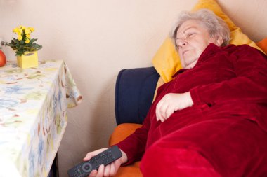 Elderly woman lying on sofa and sleeps