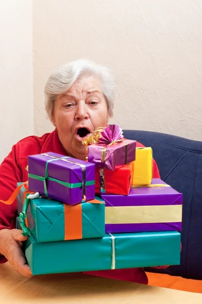 Senior sitting on the couch with gifts — 스톡 사진