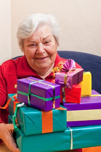 Senior sits and gets or give many gifts — Foto Stock
