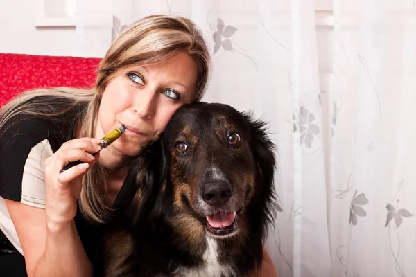 Young blonde woman with mixed breed dog evaporated E Cigarette — Stock fotografie
