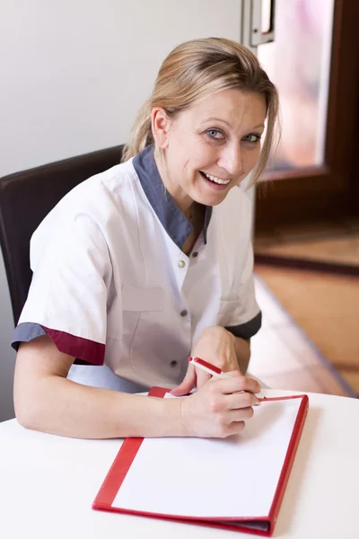 Geriatric nurse makes notes about a patient — 图库照片