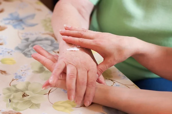 Geriatric nurse anoints elderly woman's hand — Photo