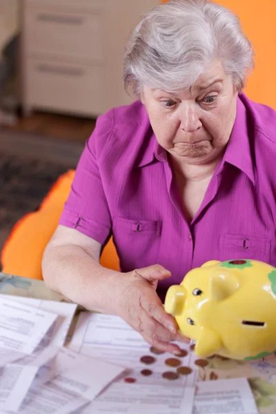 Depressed senior citizen looking for piggy bank — Stock Photo, Image