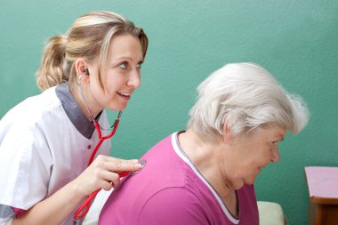 doctor examining senior with stethoscope