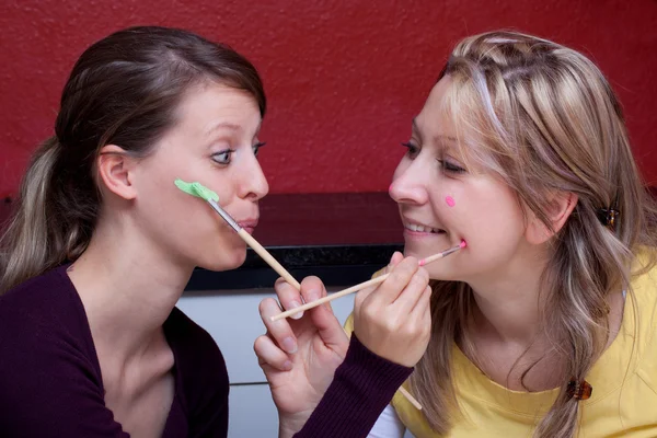 Two women paint each other's face — Stockfoto