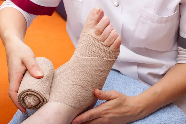 Doctor bandaged foot of a patient — Stock Fotó