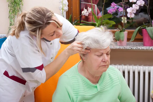 Nurse massages the head of a senior — Photo