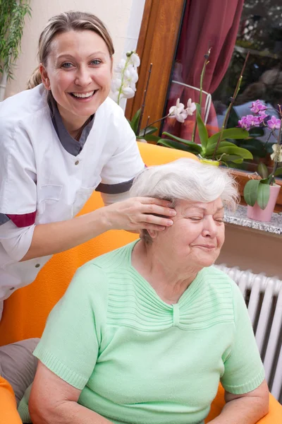 Nurse massages the head of a senior — Zdjęcie stockowe