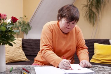 Disabled woman painted with pencils in a book