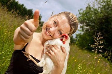 Woman with chicken lifts thumb up
