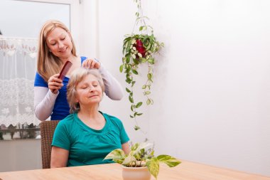 young woman combing seniors hair