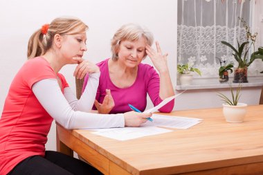 Two women pondering over documents