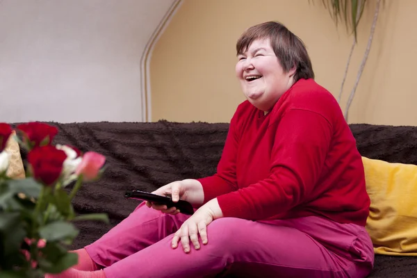 Mentally disabled woman watching television and enjoys — Stok fotoğraf