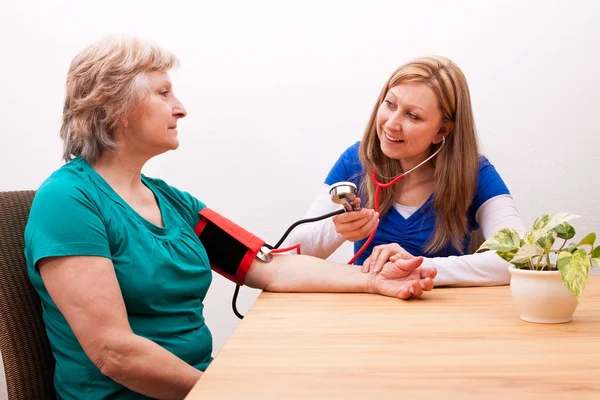 Nurse measures senior the blood pressure — Stock fotografie