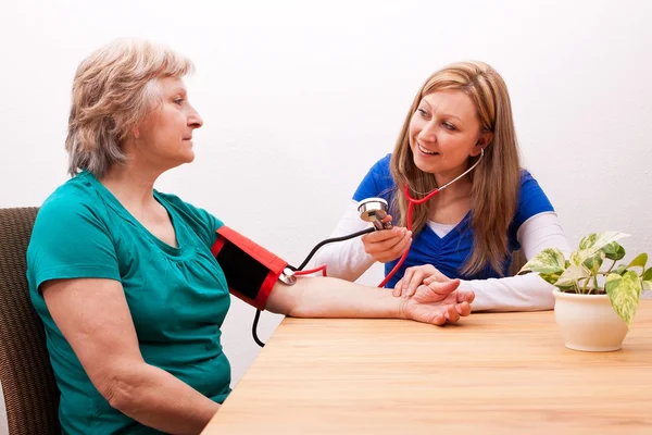 Nurse measures senior the blood pressure — Stok fotoğraf