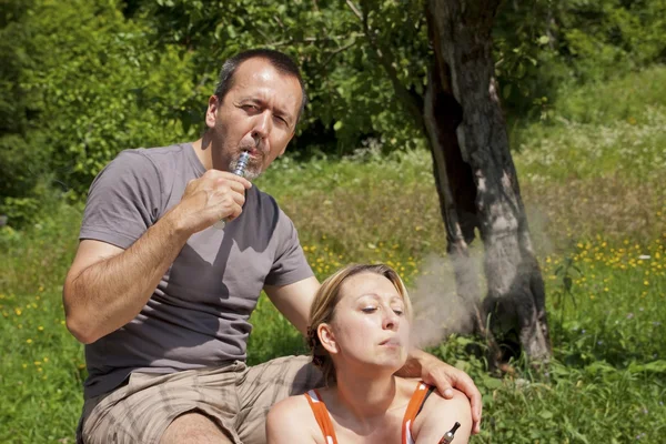 Couple in nature with e-cigarettes — Stockfoto