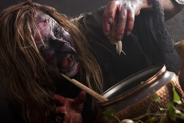 Witch brews a potion with a snail — Stock Photo, Image