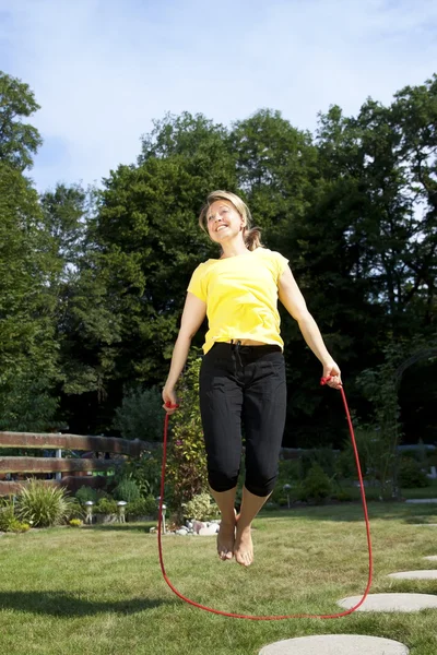 Woman jumping rope in the garden Imagen de stock