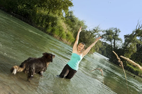 Woman playing with dog in water — Stock fotografie