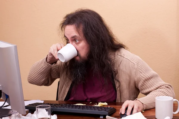 Long haired man at dirty desk — стоковое фото