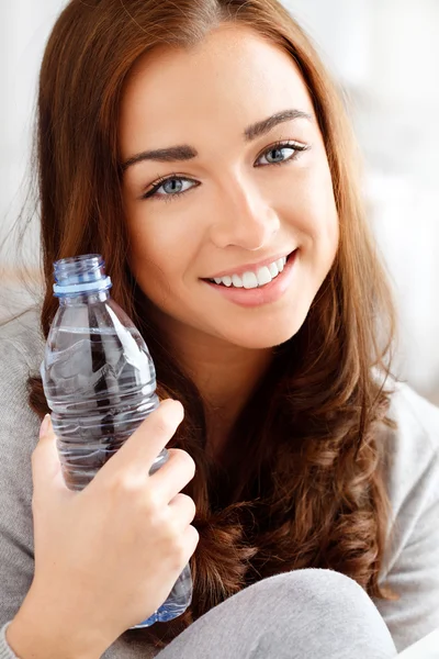 Bonita jovencita sosteniendo una botella de agua y sonriendo —  Fotos de Stock