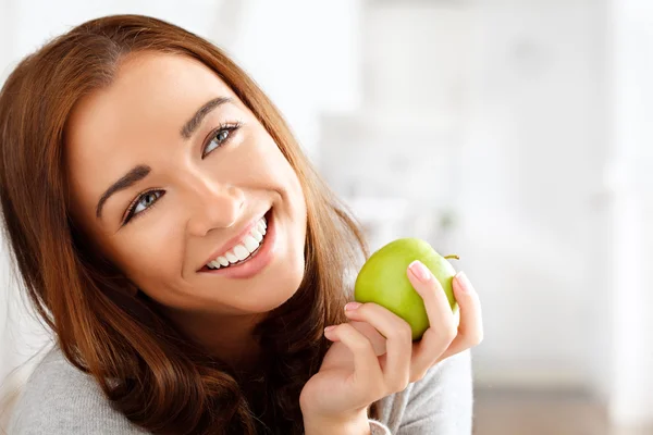 Mujer joven bastante saludable sonriendo sosteniendo una manzana verde —  Fotos de Stock