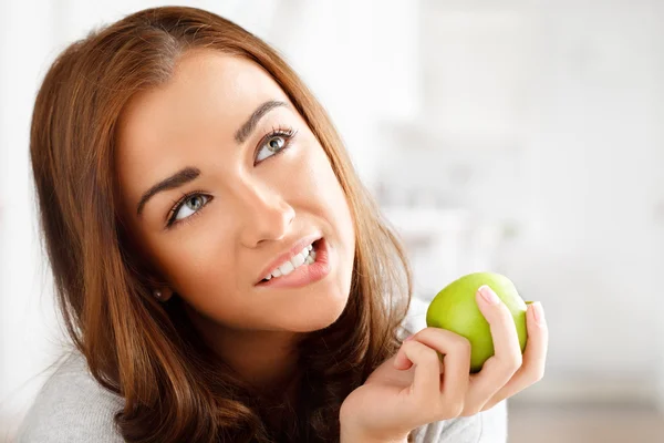 Hübsche gesunde junge Frau lächelt und hält einen grünen Apfel — Stockfoto