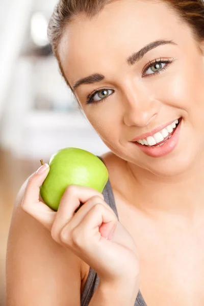 Довольно здоровая молодая женщина улыбается держа зеленое яблоко — стоковое фото