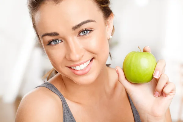 Mujer joven bastante saludable sonriendo sosteniendo una manzana verde —  Fotos de Stock