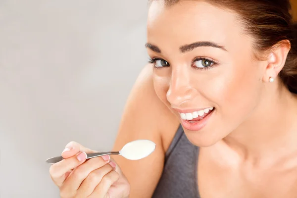 Крупный план портрета привлекательной молодой женщины, которая ест йогурт — стоковое фото