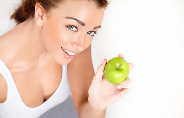 Muito saudável jovem mulher sorrindo segurando uma maçã verde — Fotografia de Stock