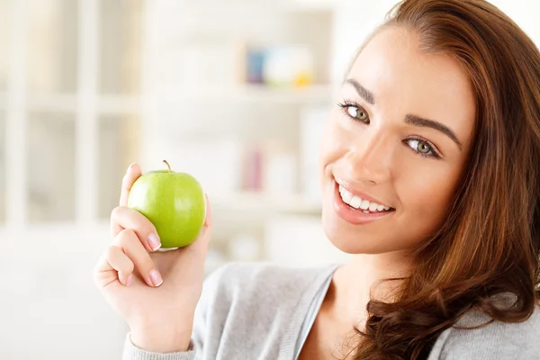 Hübsche gesunde junge Frau lächelt und hält einen grünen Apfel — Stockfoto
