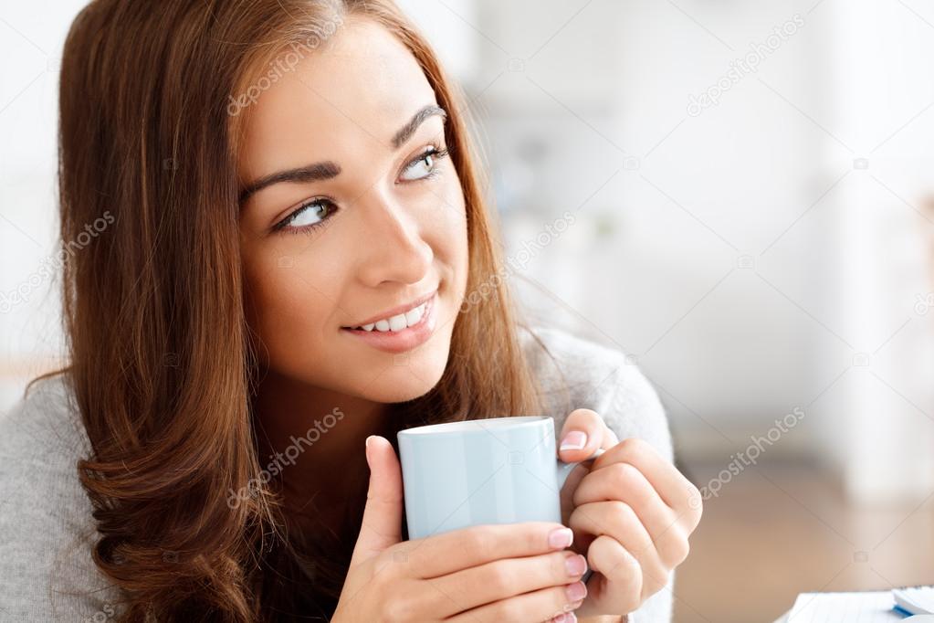 Attractive young woman drinking coffee at home