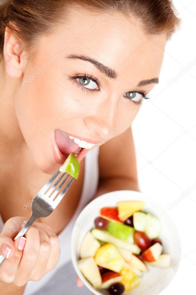 Slim young woman eating fruit salad