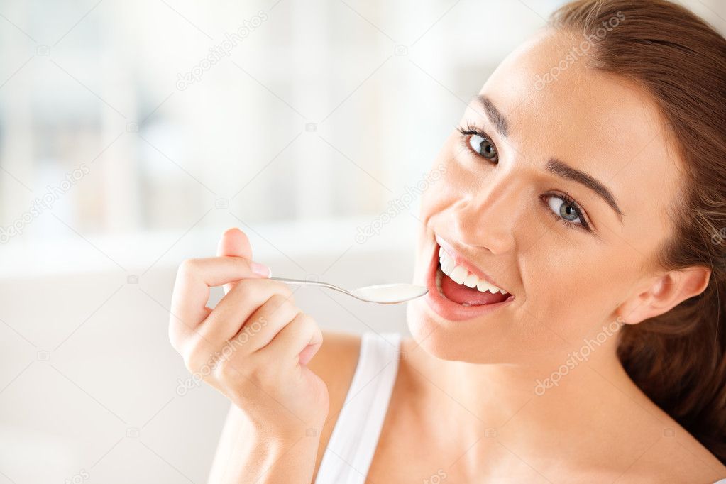 Close-up portrait of an attractive young woman eating yogurt