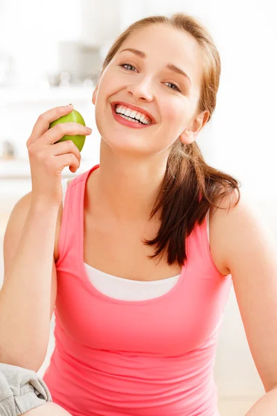 Pretty healthy young woman smiling holding a green apple — Stock Photo, Image